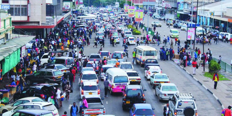Heavy traffic and pedestrians along a busy street in Harare city centre, Zimbabwe, showing daily urban transport activity and vehicle congestion.